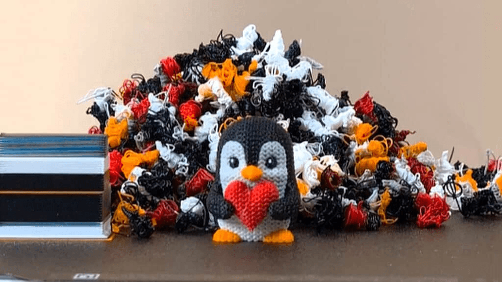 Multi-Material 3D Printer vs Multi-Colour 3D Printer Simplified 7 Close up of a multi color print of a penguin holding a red heart on a bambu lab a1 with a pile of purged filament in the background 1024x577